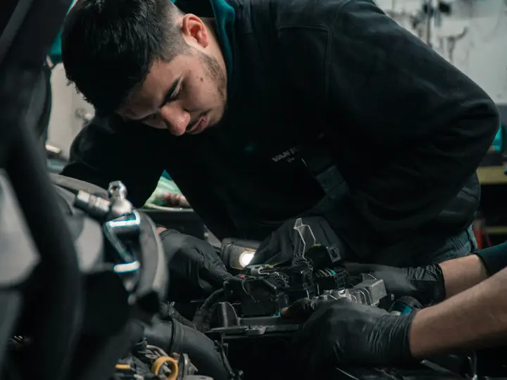 Mecánico trabajando sobre el motor de un coche con el capó abierto